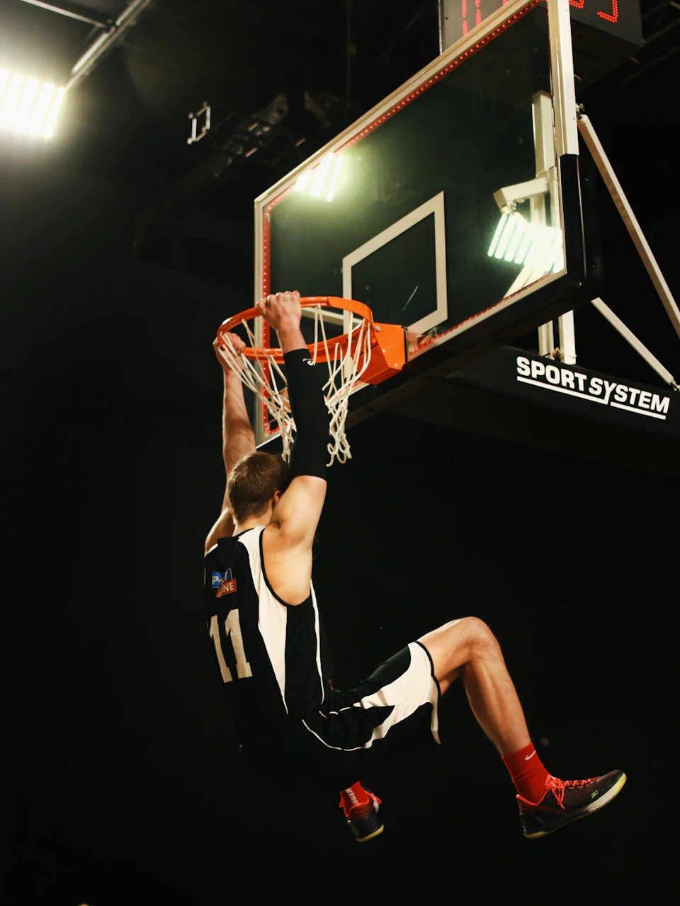 A basketball player hanging on the rim after a dunk