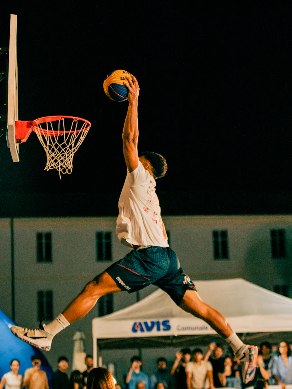 A player soaring to dunk at an outdoor night game